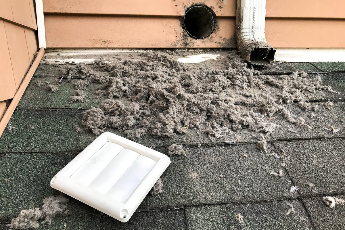 ANC technician using professional rotary brush equipment to clean a dryer vent duct in an older Binghamton NY home laundry room during a spring safety inspection