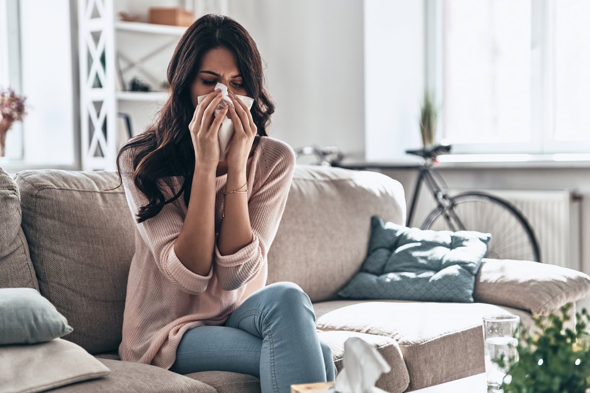 Homeowner experiencing seasonal allergy symptoms indoors at a Binghamton area home with an HVAC return air vent and air filter visible in the background