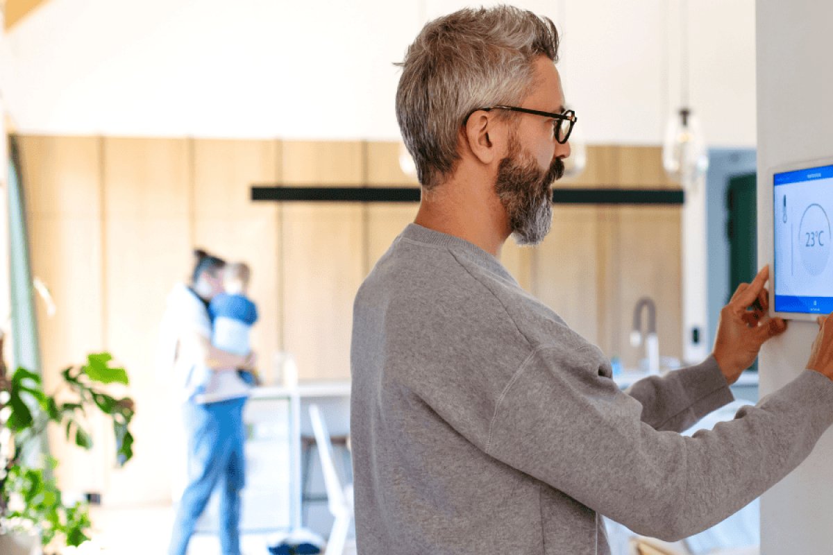 Man adjusting smart thermostat to improve home comfort