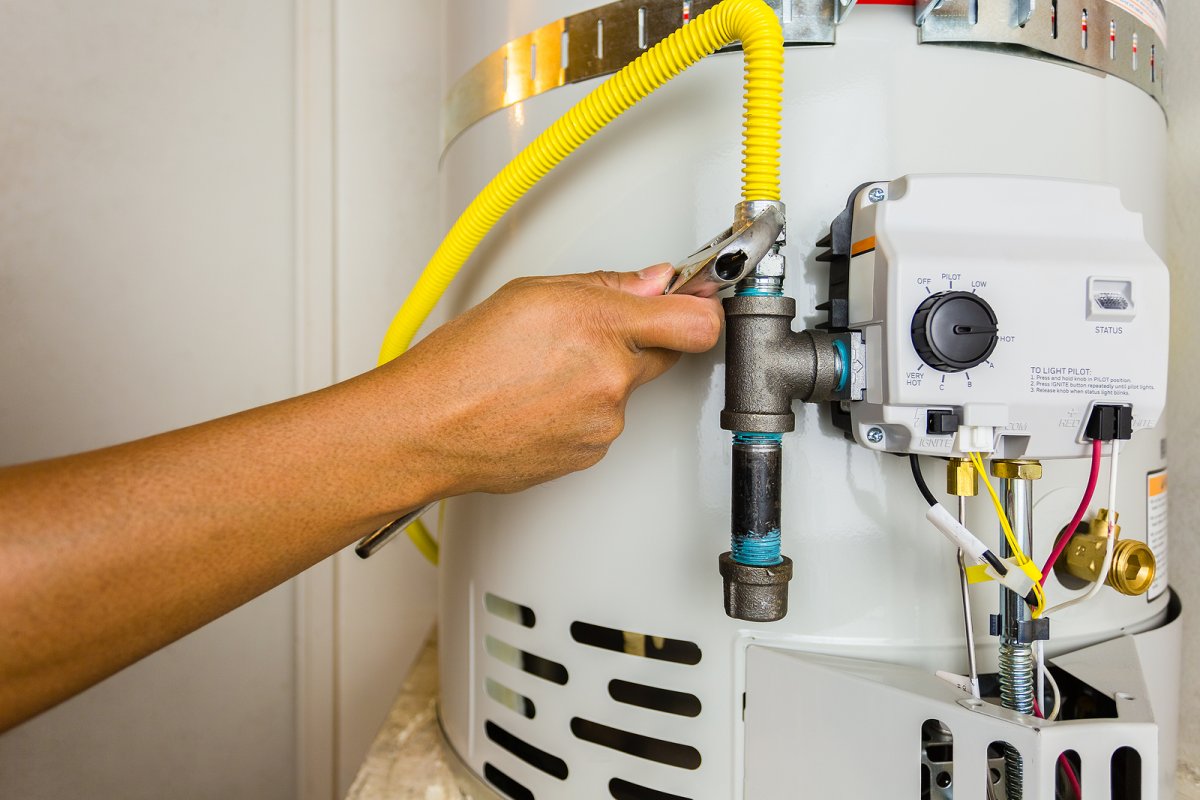Plumber inspecting an aging tank style water heater in the basement of a Binghamton NY home